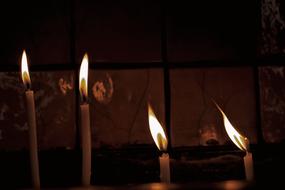 Close-up of the burning candles among the darkness