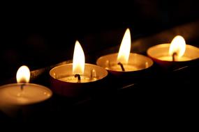 Close-up of the burning candles, among the darkness