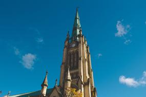 Beautiful and colorful cathedral with the steeple, in sunlight, under the blue sky with white clouds