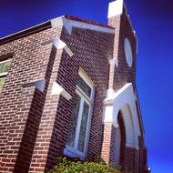 Colorful, brick Presbyterian church with the colorful plant, in sunlight, under the blue sky