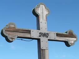 wooden cross with an inscription on a blue sky background