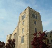 Beautiful church with the tower, among the colorful trees, under the blue sky with white clouds