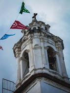 Beautiful bell tower and colorful flags, under the blue sky with clouds