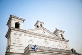 Beautiful church with balcony and colorful birds, under the blue sky