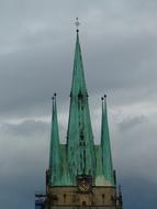 Beautiful church with green steeple, under the sky with dark clouds
