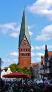 People near the beautiful and colorful church with steeple among the other buildings in LÃ¼neburg, Germany