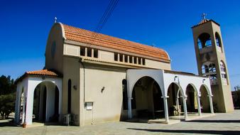 Beautiful and colorful church in Larnaca, Cyprus, among the trees, in sunlight, under the blue sky