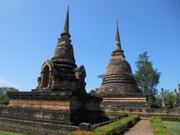 Beautiful and colorful landscape of the temple among the plants, in Sukothai, Thailand, under the blue sky