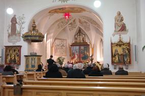 parishioners sit on benches in the church