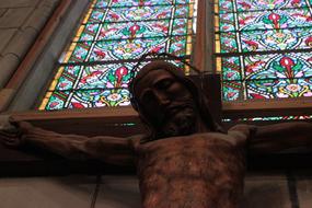 Statue of Jesus Christ near the colorful and beautiful stained glass windows with patterns