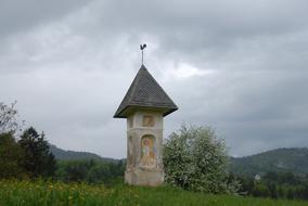 Beautiful chapel, among the colorful plants on the mountains, under the sky with clouds