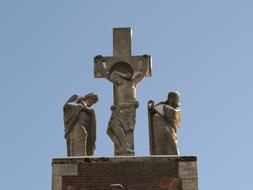 Statue with Jesus Christ on the cross, among the people, at background with blue sky