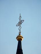 Close-up of the cross on the steeple of the church, under the blue sky