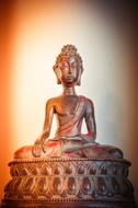 Beautiful, shiny statue in meditation, at colorful background