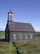 Beautiful church on the colorful field in Iceland, under the blue sky with clouds