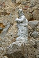 Beautiful statue of the man, on the colorful rocks with plants