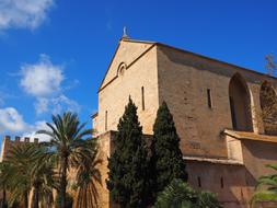 Beautiful EsglÃ©sia De Sant Jaume among the colorful and beautiful plants in Mallorca, in sunlight, under the blue sky with clouds
