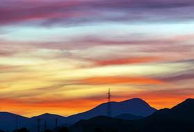 electric towers in the mountains against the backdrop of a colorful sunset