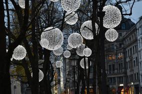 Beautiful, white lamps among the trees in the city in the evening