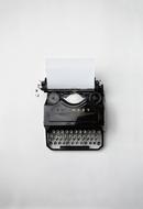 Top view of the beautiful, retro, black typewriter with white papers, on the white surface