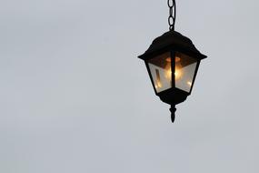 lantern hanging on a chain against a gray sky