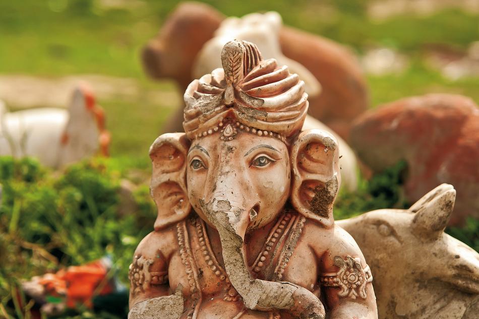 Beautiful statue of Ganesha among the plants and other statues