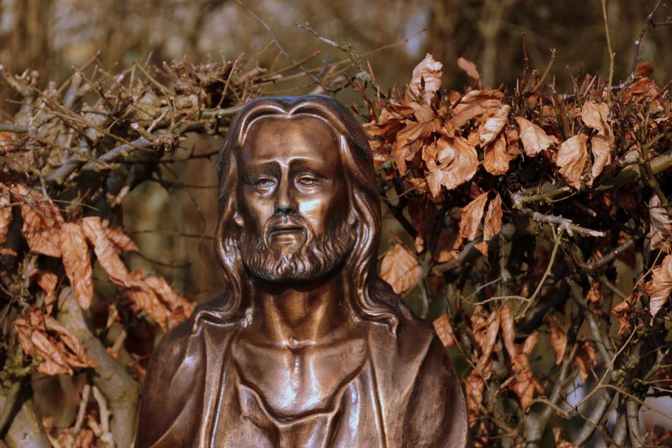 Beautiful, shiny statue of Jesus Christ, among the colorful leaves