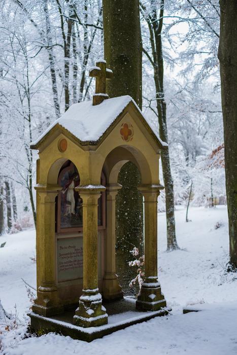 Beautiful and colorful chapel, among the trees of the forest in snow, in winter