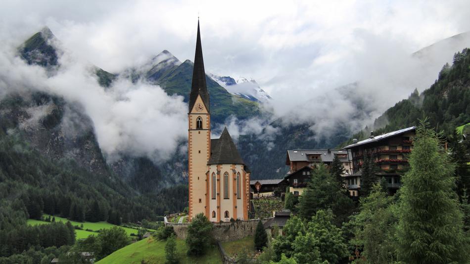 Beautiful Szentsziv Temple among the green mountains in white clouds in Heiligenblut, Austria