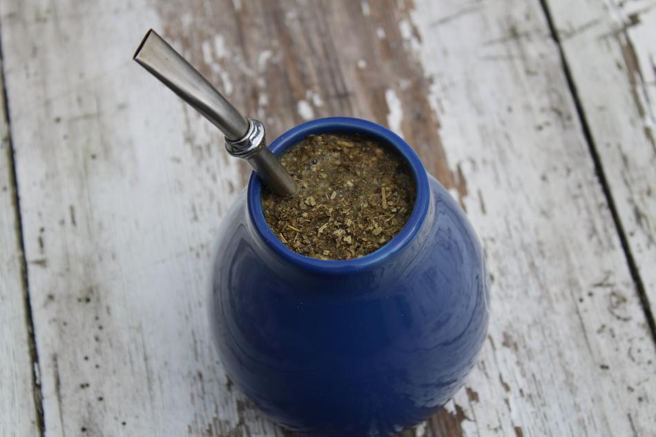 Beautiful Yerba Mate drink in the blue cup with the bombilla, on the wooden surface
