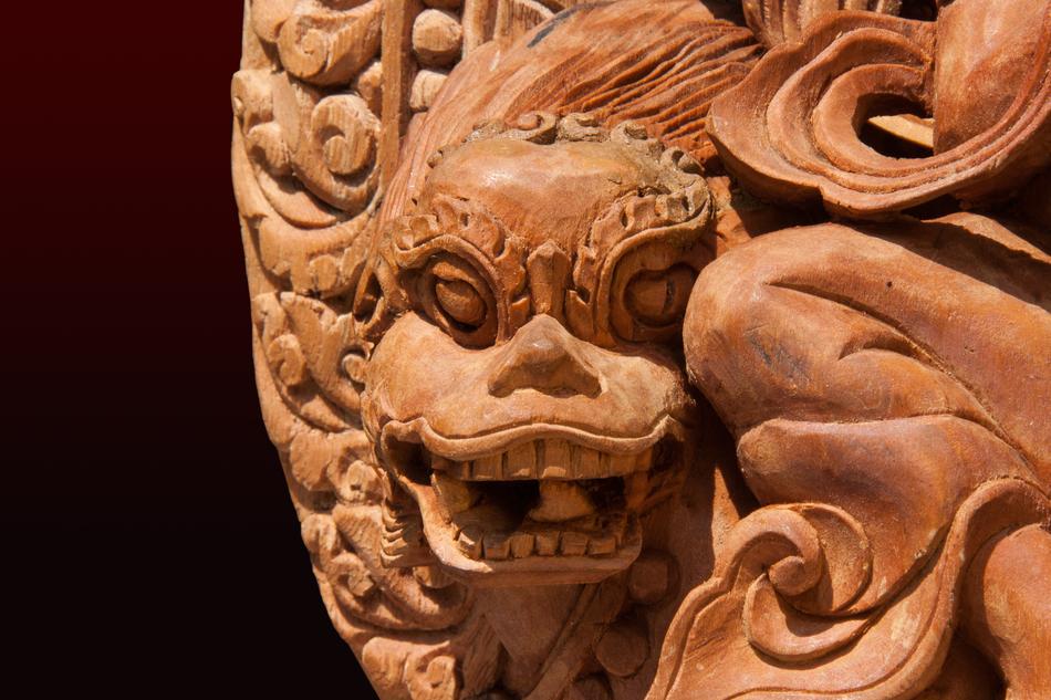 Beautiful, carved lion-dragon in the wood, in light, at black background