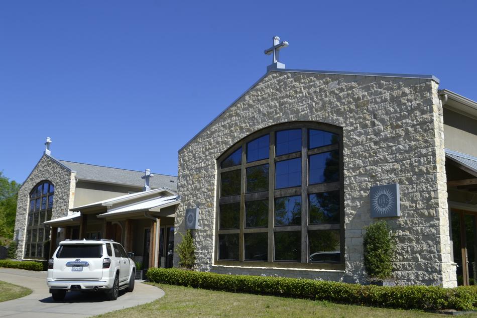 White Toyota 4 Runner car, near the beautiful chapel with the crosses and windows, and green garden