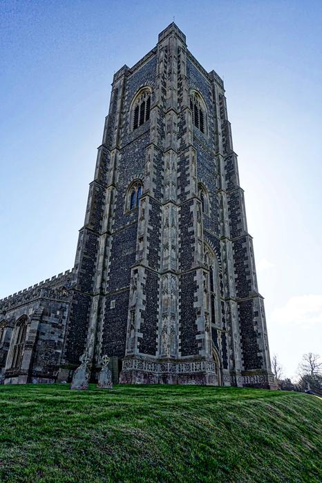 Beautiful cathedral with the spire, on the green field, at blue sky on background, in Stoke-By-Nayland, England, United Kingdom