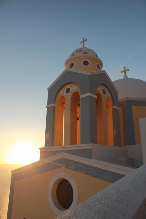 Beautiful and colorful church with the crosses, in sunlight, on the shore of the sea in Greece