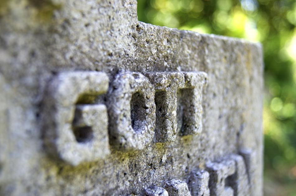'God' sign on the old, stone statue, near the green plants