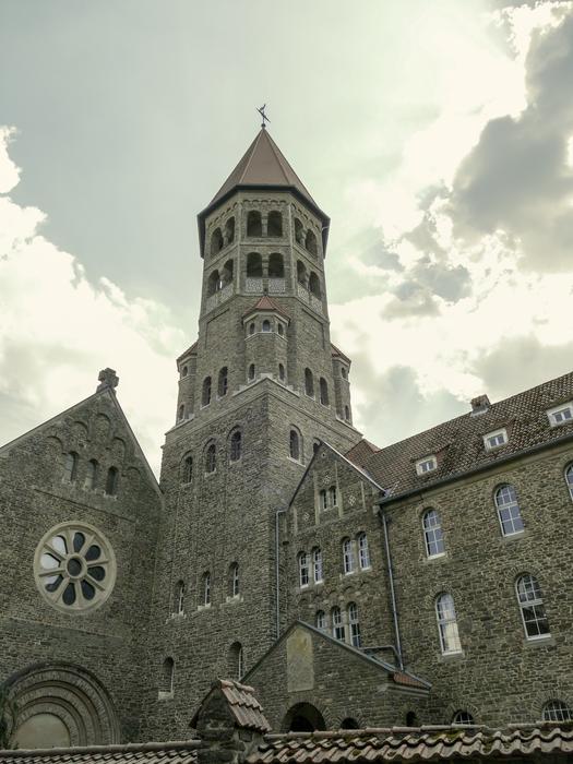 Beautiful, old church with the tower, under the sky with clouds and light
