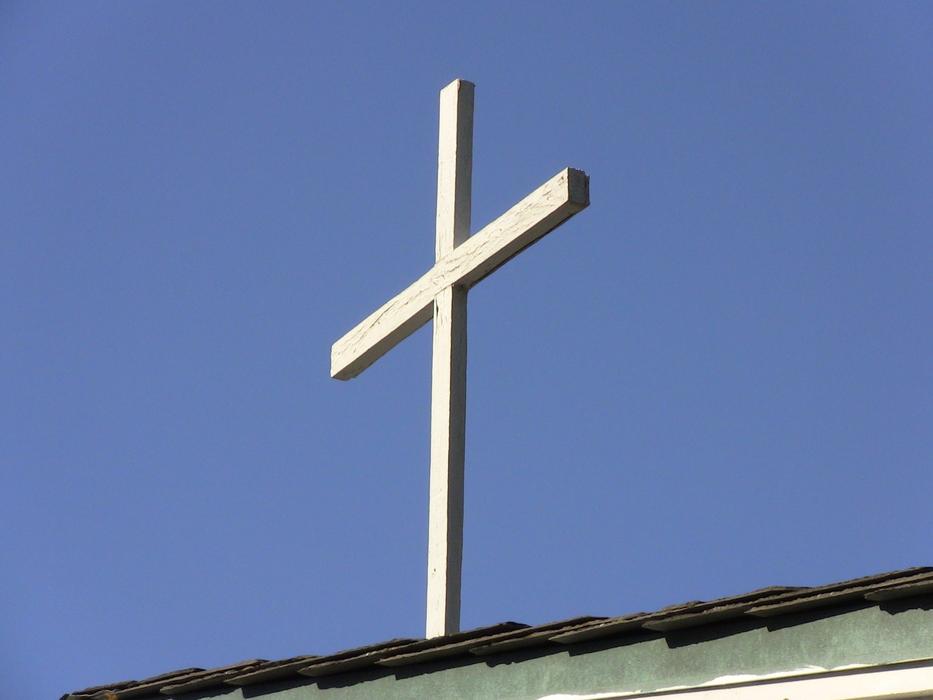 white cross on the roof against the blue sky