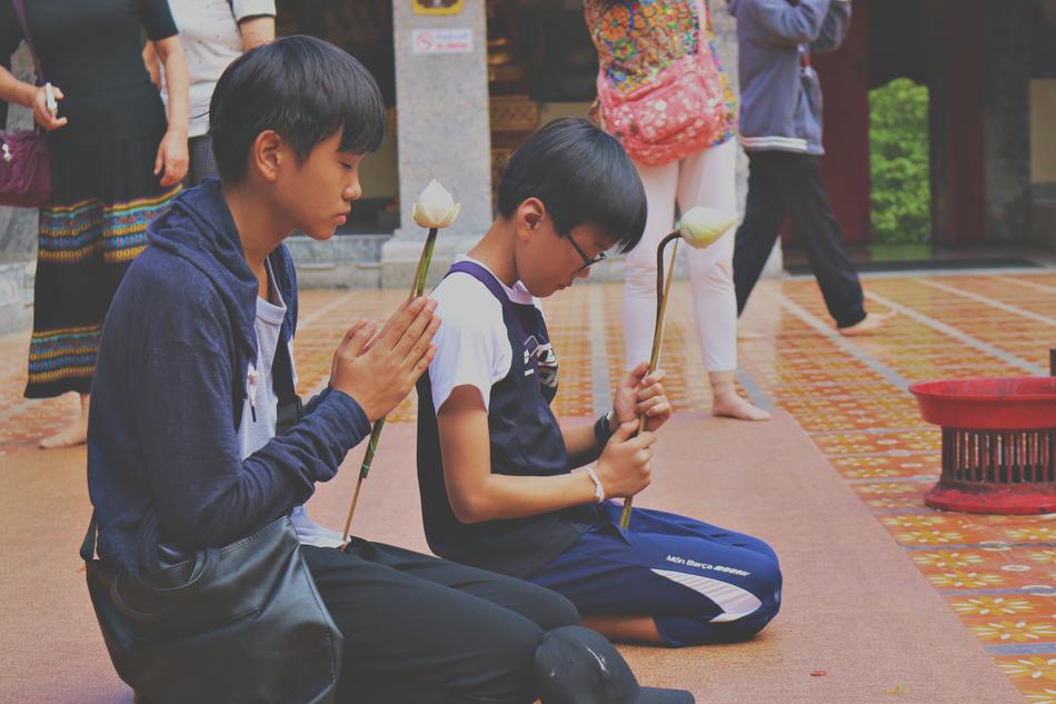 two asian boys meditating with lotus buds in hands, Thailand