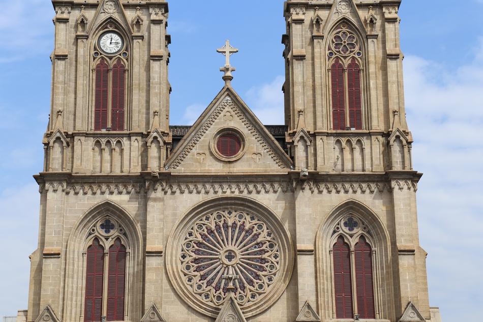 Beautiful and colorful church with the cross, on Shamian in China, under the blue sky with white clouds
