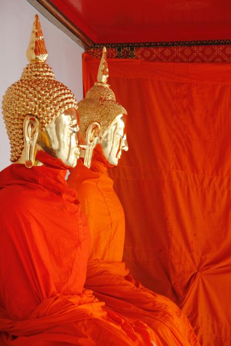 Beautiful, shiny, gold Buddha statues in red and orange clothes