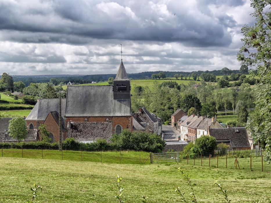 Beautiful landscape with the church, among the green trees in Eppe-Sauvage, France, under the clouds