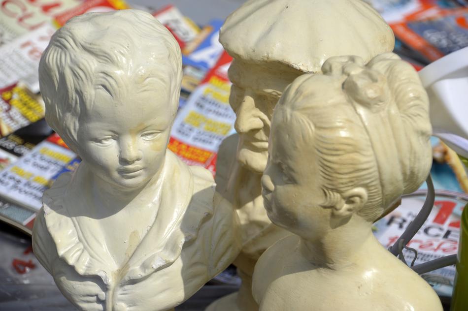 Beautiful, shiny sculptures with heads, near the colorful magazines on the flea market, in light