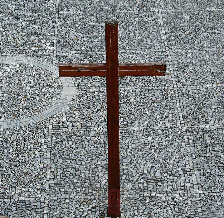 Close-up of the wooden cross on the pavement, near the church