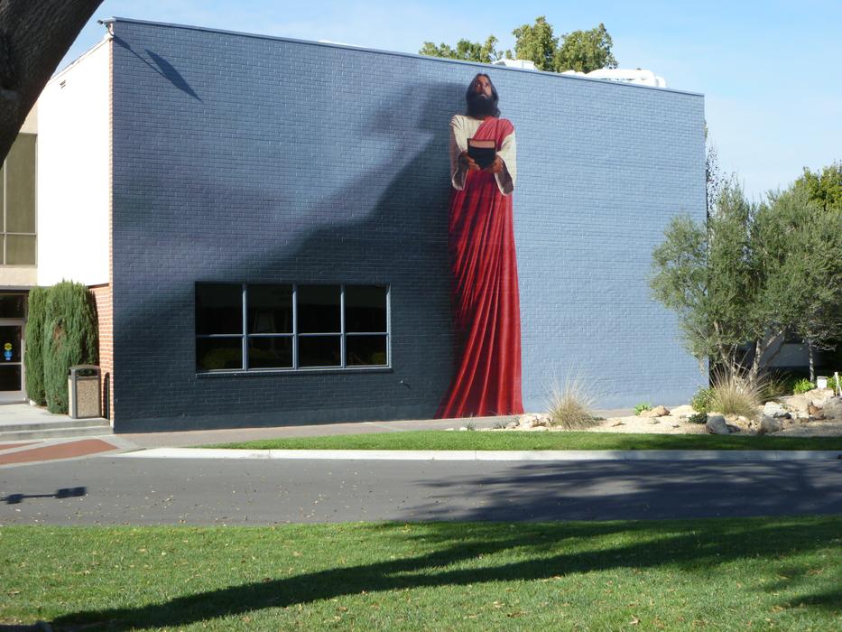 Beautiful and colorful painting of Jesus Christ, on the building, among the green plants