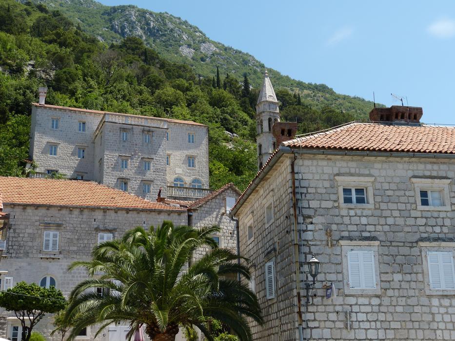 Beautiful church and other buildings, near the green mountains in Perast, Montenegro