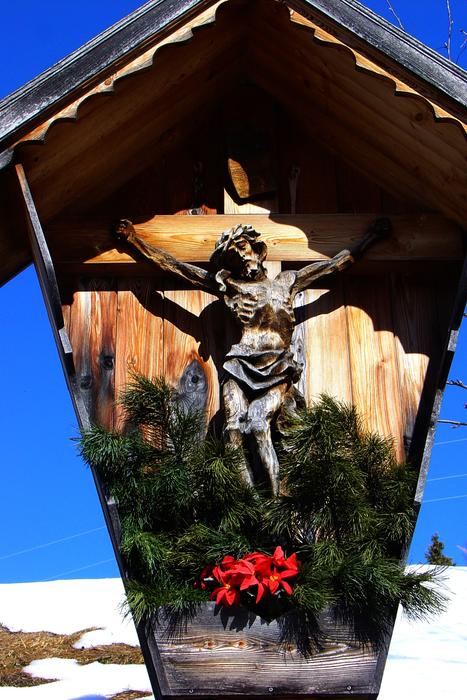Wooden construction with Jesus Christ, with the plants, near the snow, in the winter, under the blue sky