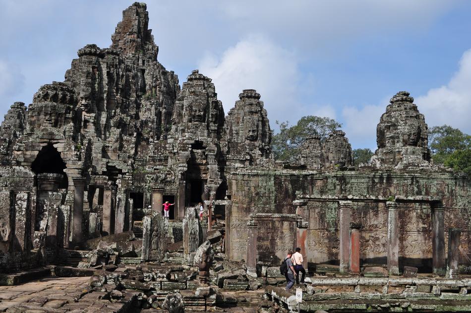 People at the beautiful and colorful Angkor Wat temple among the plants, in Cambodia, under the blue sky with white clouds