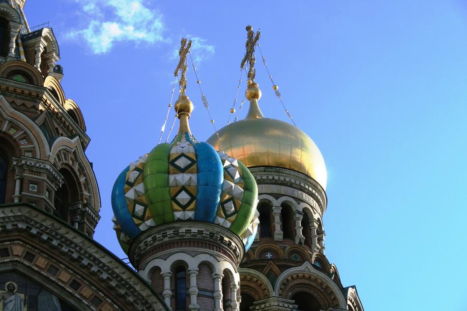 Beautiful and colorful church with shiny domes and crosses, in sunlight, under the blue sky with white clouds