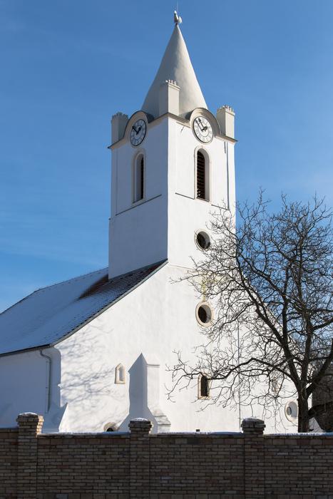 Beautiful, white church in sunlight, among the plants in Šamorín, Slovakia