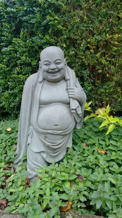 Beautiful statue of Buddha among the colorful plants in the temple in SÃ£o Paulo, Brazil